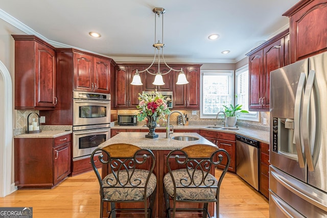 kitchen featuring sink, a kitchen breakfast bar, hanging light fixtures, a kitchen island with sink, and stainless steel appliances