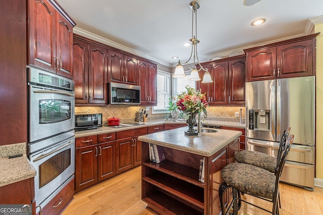 kitchen featuring tasteful backsplash, decorative light fixtures, a center island, light hardwood / wood-style flooring, and black appliances