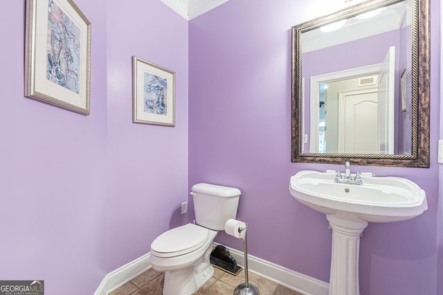 bathroom with tile patterned flooring, crown molding, and toilet