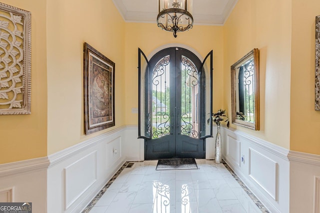 foyer featuring crown molding, french doors, and a chandelier