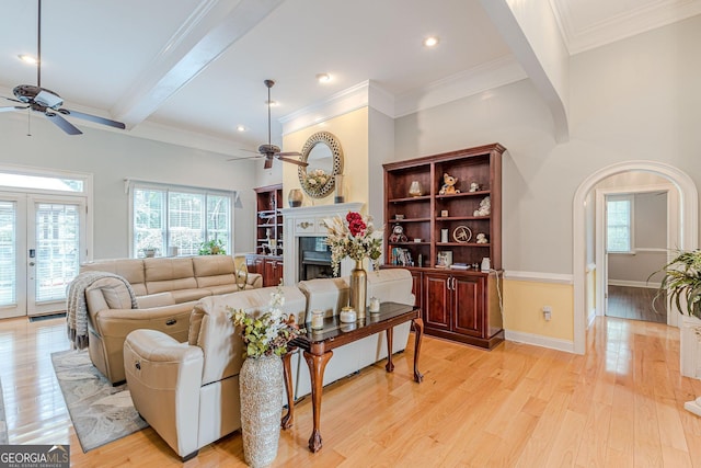 living room featuring beamed ceiling, ornamental molding, ceiling fan, and light hardwood / wood-style flooring