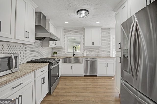 kitchen with white cabinetry, stainless steel appliances, and wall chimney exhaust hood