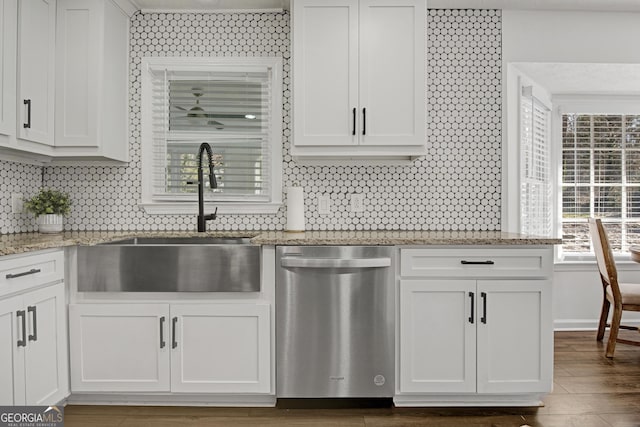 kitchen with sink, white cabinetry, light stone counters, stainless steel dishwasher, and dark hardwood / wood-style floors