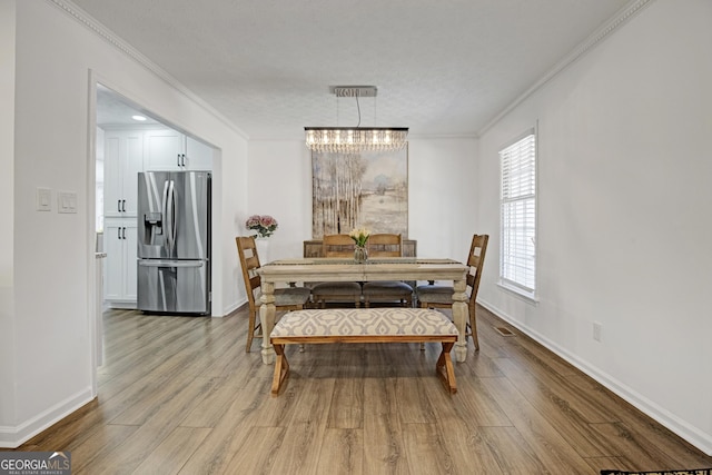 dining space featuring crown molding and light hardwood / wood-style flooring