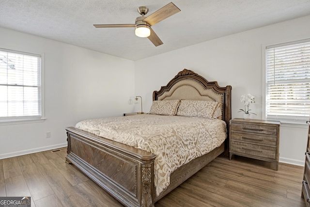 bedroom featuring a textured ceiling, wood-type flooring, and ceiling fan