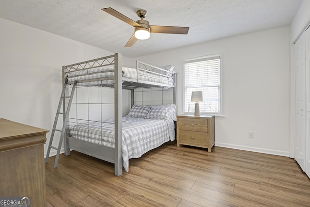 bedroom featuring hardwood / wood-style flooring, a closet, ceiling fan, and a textured ceiling