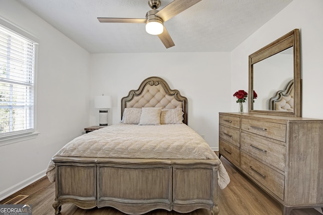 bedroom with dark hardwood / wood-style floors, a textured ceiling, and ceiling fan