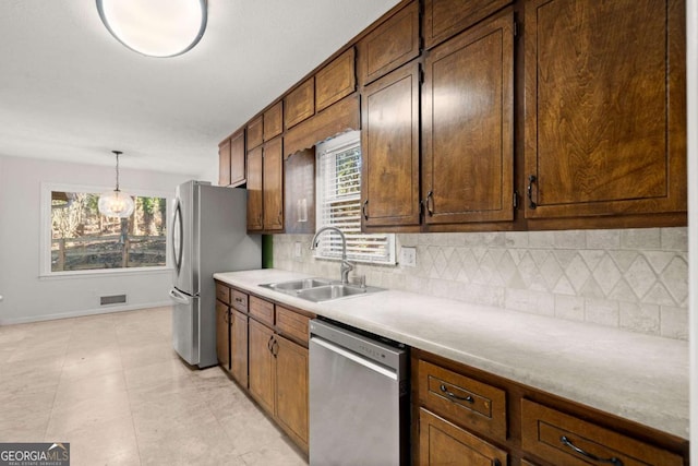 kitchen featuring hanging light fixtures, tasteful backsplash, appliances with stainless steel finishes, and sink