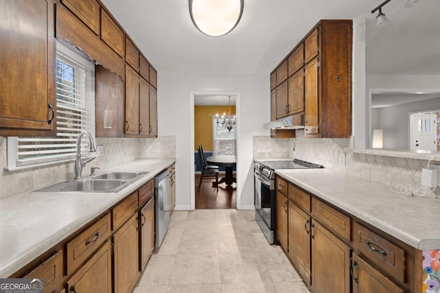 kitchen featuring sink, decorative backsplash, light tile patterned floors, a notable chandelier, and stainless steel appliances