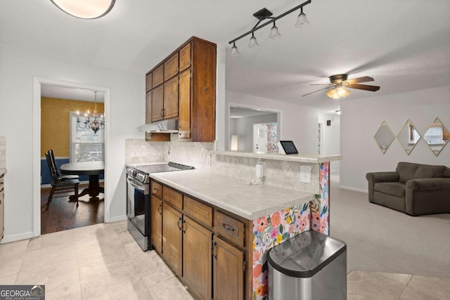 kitchen with electric range, pendant lighting, light colored carpet, ceiling fan with notable chandelier, and decorative backsplash