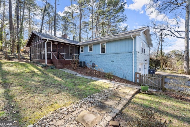 rear view of property featuring a garage, a yard, a sunroom, and central air condition unit