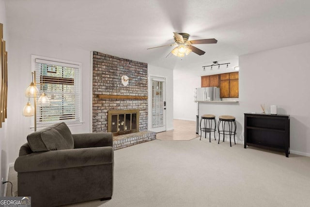 carpeted living room with ceiling fan, track lighting, and a fireplace