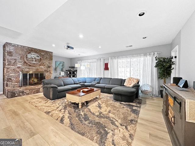 living room with a stone fireplace and light hardwood / wood-style floors