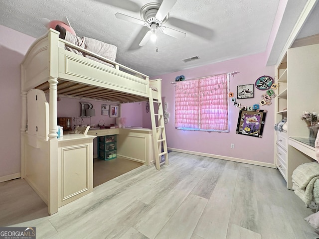 unfurnished bedroom with ceiling fan, a textured ceiling, and light wood-type flooring