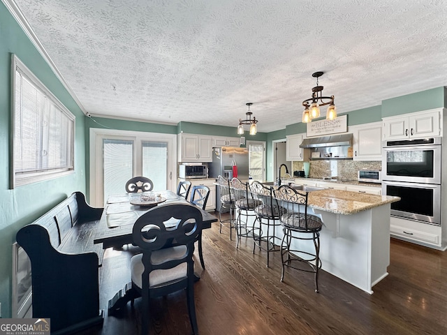 dining space featuring dark wood-type flooring, sink, and a textured ceiling