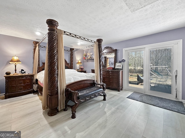 bedroom featuring access to outside, light hardwood / wood-style floors, and a textured ceiling