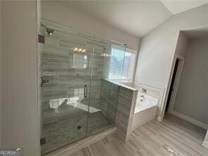 bathroom featuring lofted ceiling, hardwood / wood-style flooring, and plus walk in shower