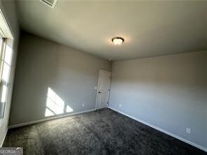 unfurnished room featuring dark colored carpet