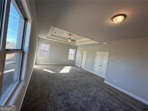 carpeted empty room with ceiling fan and a tray ceiling