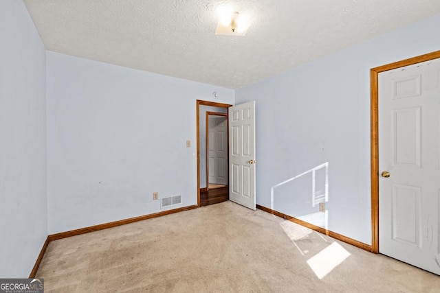 spare room featuring light carpet and a textured ceiling