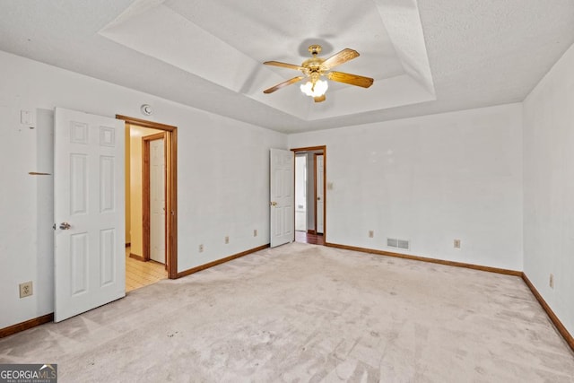 carpeted spare room with ceiling fan, a raised ceiling, and a textured ceiling