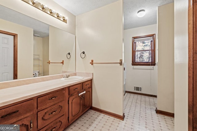 bathroom featuring vanity, a textured ceiling, and toilet