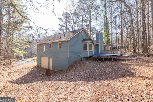 view of property exterior featuring a garage, central AC, and a trampoline