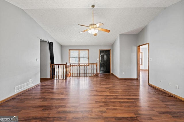 empty room with dark wood-type flooring, ceiling fan, lofted ceiling, and a textured ceiling