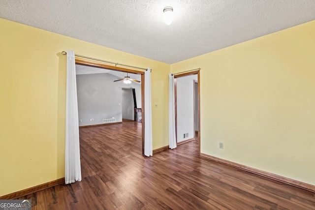 empty room with dark hardwood / wood-style floors and a textured ceiling