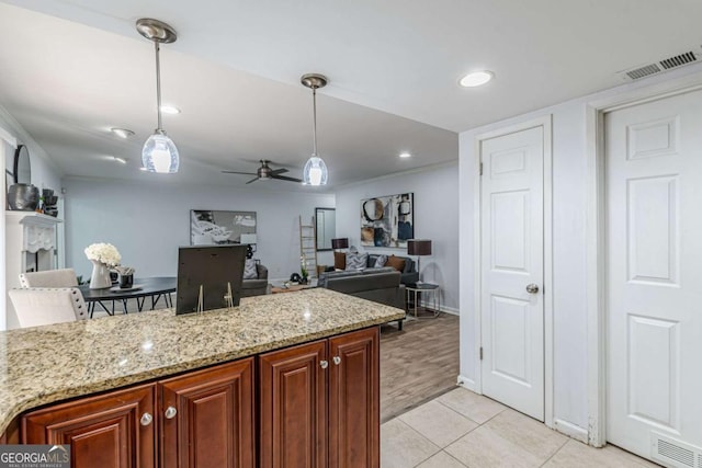 kitchen featuring pendant lighting, ceiling fan, light stone counters, and light tile patterned floors