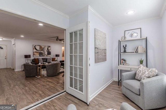 living area featuring crown molding, ceiling fan, and light wood-type flooring