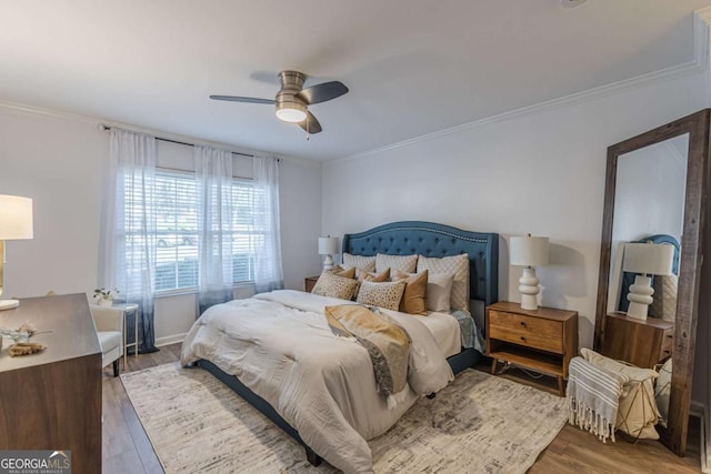 bedroom with hardwood / wood-style flooring, ornamental molding, and ceiling fan