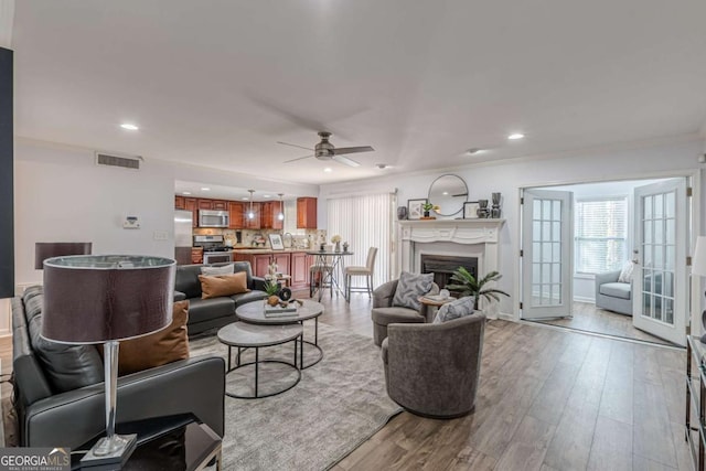 living room with crown molding, ceiling fan, and light wood-type flooring