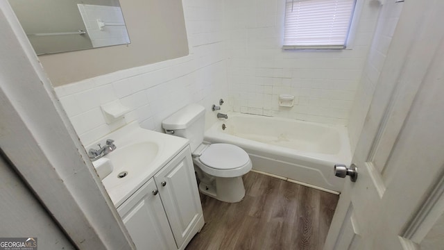 full bathroom with toilet, wood-type flooring, tile walls, vanity, and tiled shower / bath combo