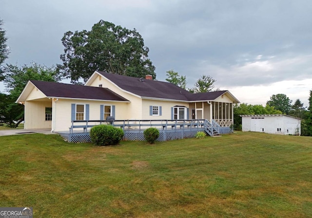 back of house featuring a sunroom, a deck, and a lawn