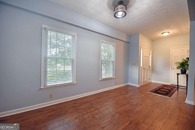 foyer with dark wood-type flooring, a wealth of natural light, and a textured ceiling