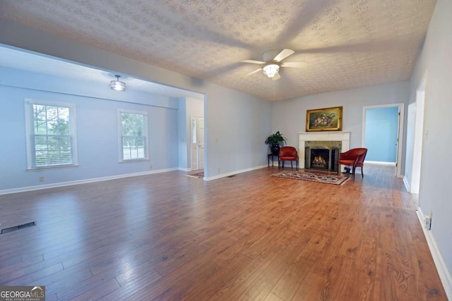 living room with ceiling fan, dark hardwood / wood-style floors, and a textured ceiling