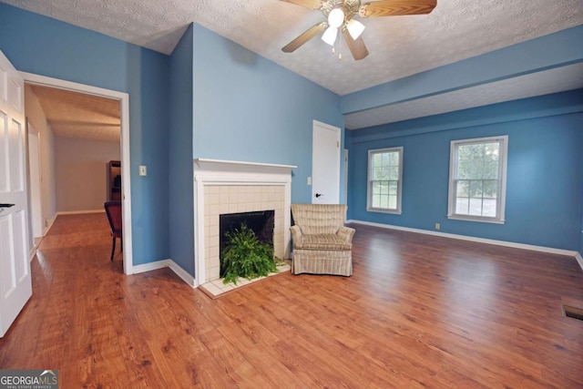 unfurnished living room with ceiling fan, hardwood / wood-style floors, and a textured ceiling