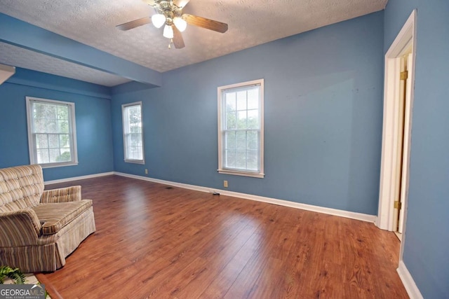 unfurnished room with ceiling fan, hardwood / wood-style floors, a textured ceiling, and a wealth of natural light