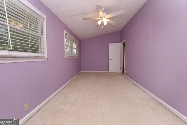 carpeted empty room featuring ceiling fan, vaulted ceiling, and a textured ceiling