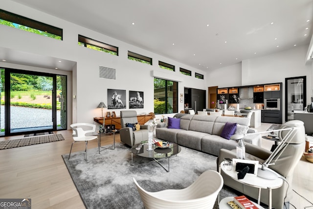 living room with a healthy amount of sunlight, wood-type flooring, and a high ceiling