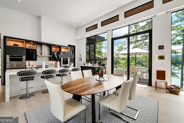 dining area with a high ceiling, plenty of natural light, and light hardwood / wood-style floors