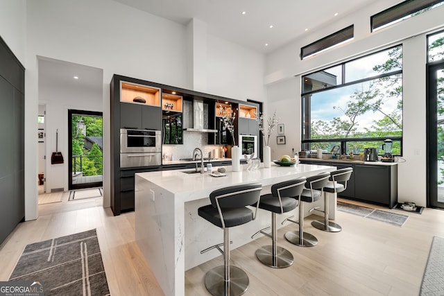 kitchen featuring a towering ceiling, a kitchen breakfast bar, and a center island with sink