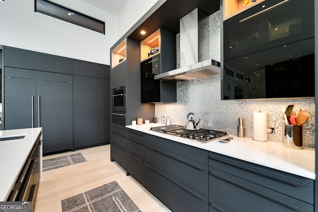 kitchen with sink, tasteful backsplash, appliances with stainless steel finishes, light hardwood / wood-style floors, and wall chimney range hood