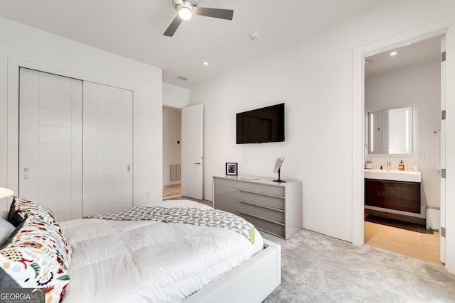 carpeted bedroom with connected bathroom, ceiling fan, and a closet