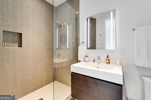 bathroom with vanity, toilet, and a tile shower