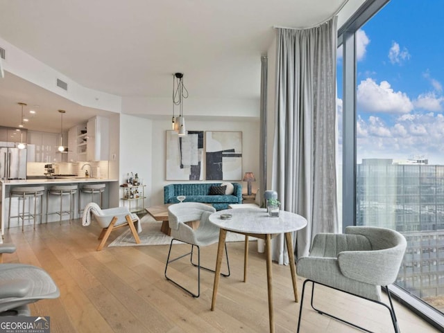 dining area with expansive windows, a wealth of natural light, sink, and light wood-type flooring