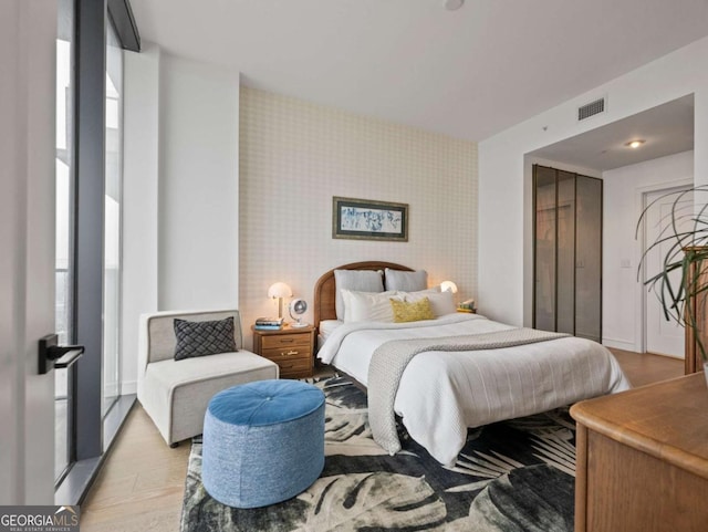 bedroom featuring expansive windows and light hardwood / wood-style floors