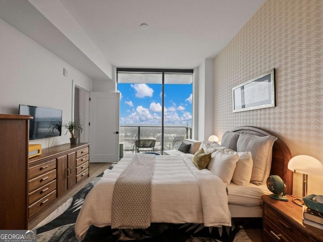 bedroom featuring access to outside, a wall of windows, and light hardwood / wood-style flooring