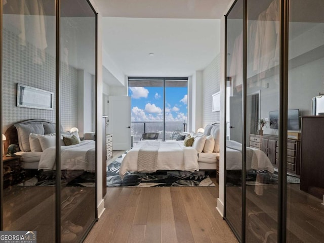 bedroom with floor to ceiling windows and light hardwood / wood-style floors